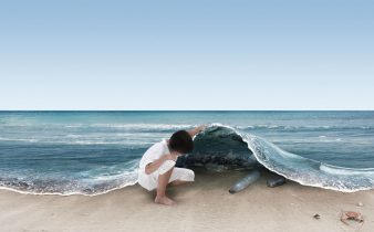 Bambino sulla spiaggia che osserva il mare inquinato